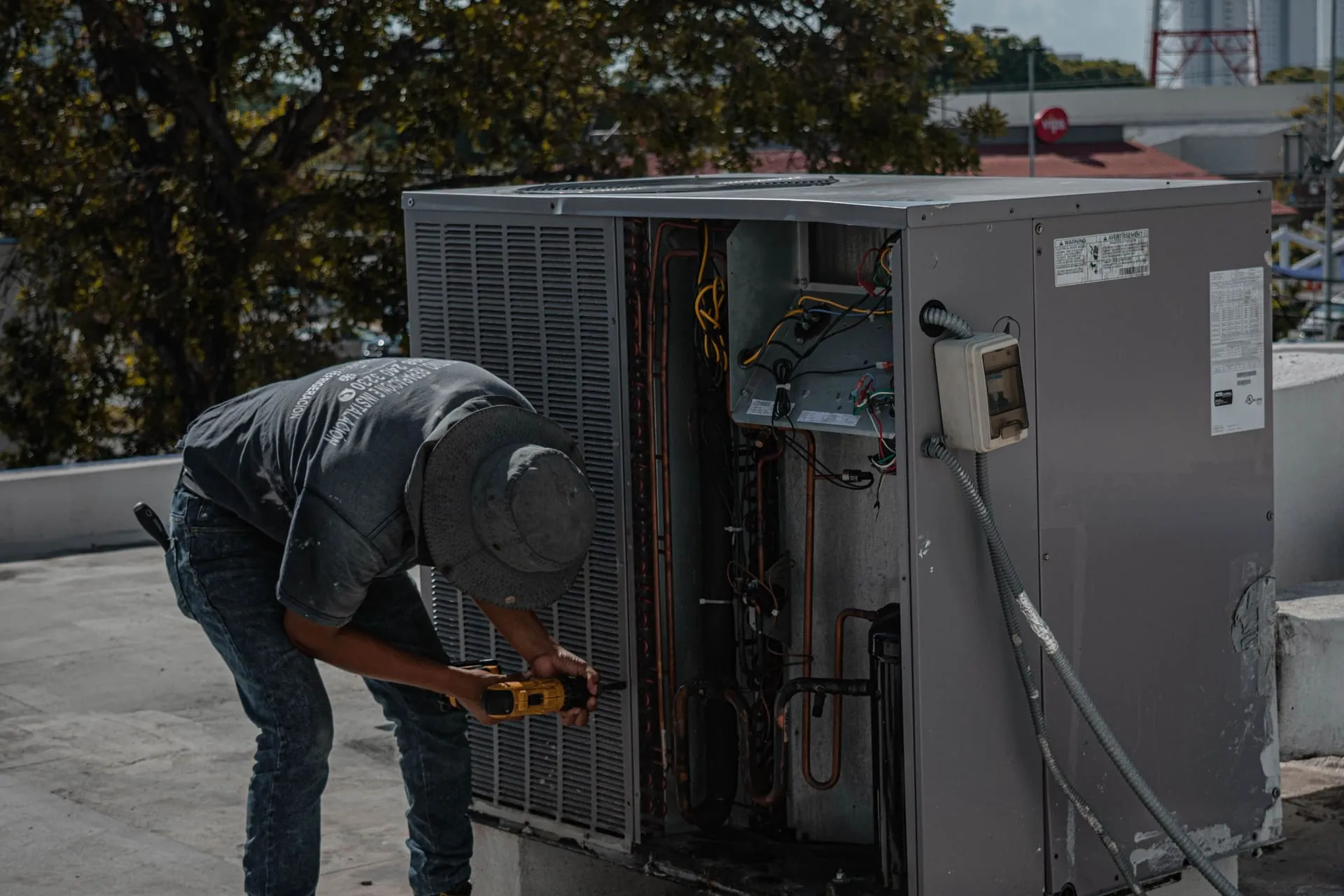 Technician repairing an outdoor air conditioner unit with its service panel removed