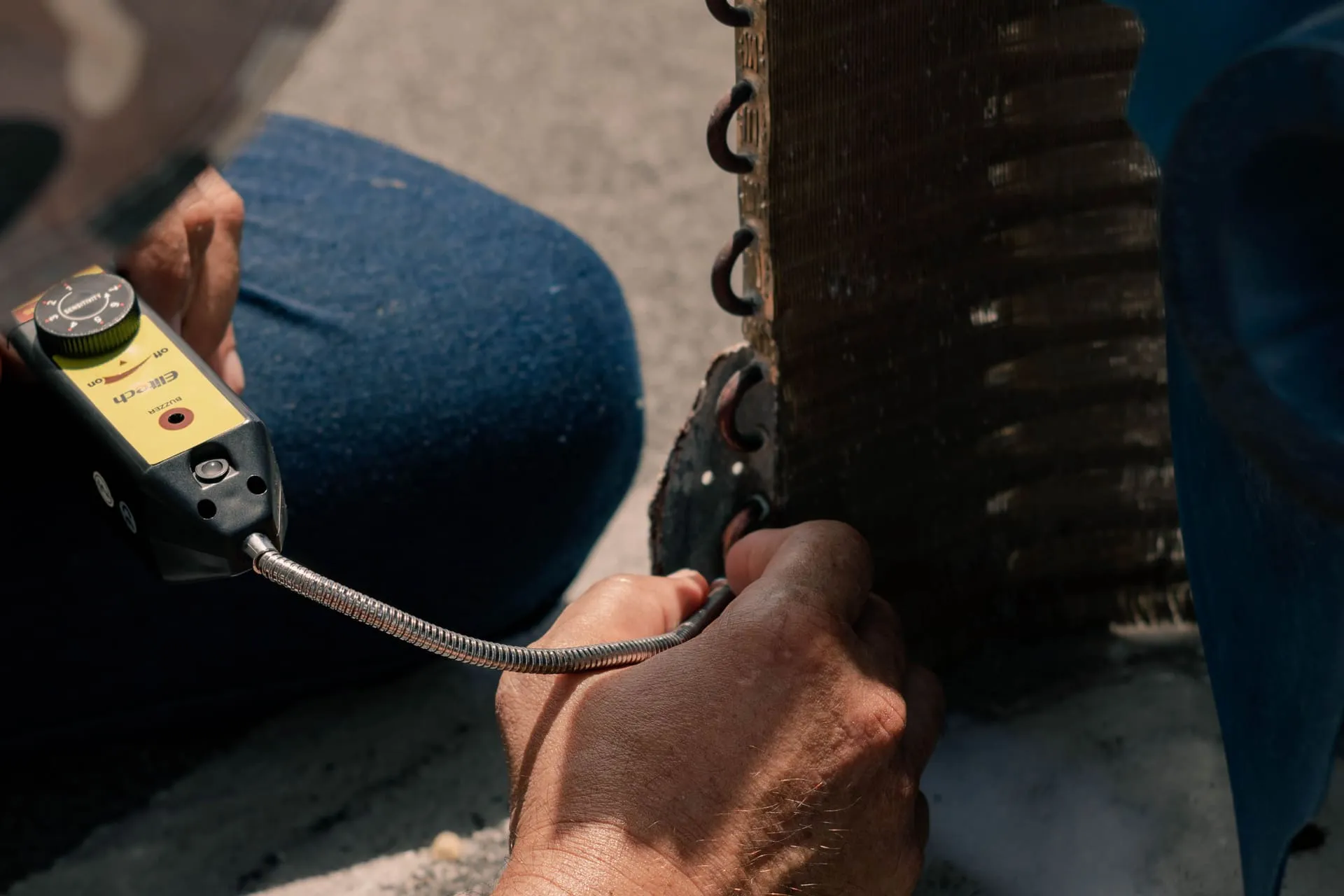 Technician checking a coil with a leak detector for an air conditioner leaking water