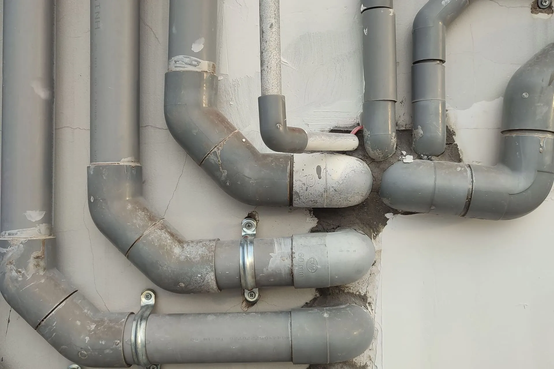 Grey PVC drain pipes and fittings running along a wall