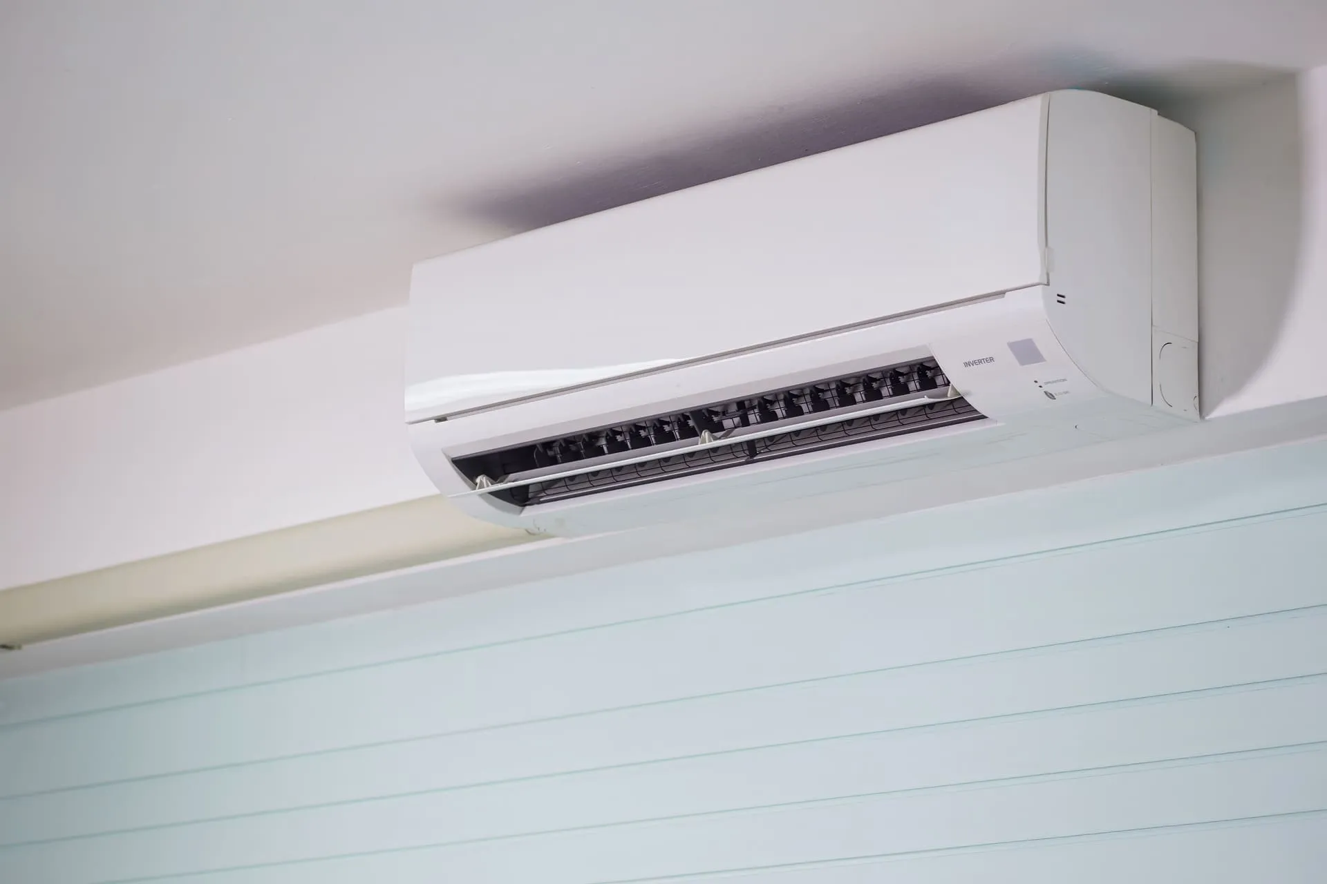Wall-mounted split system air conditioner with its louvre open on a white wall
