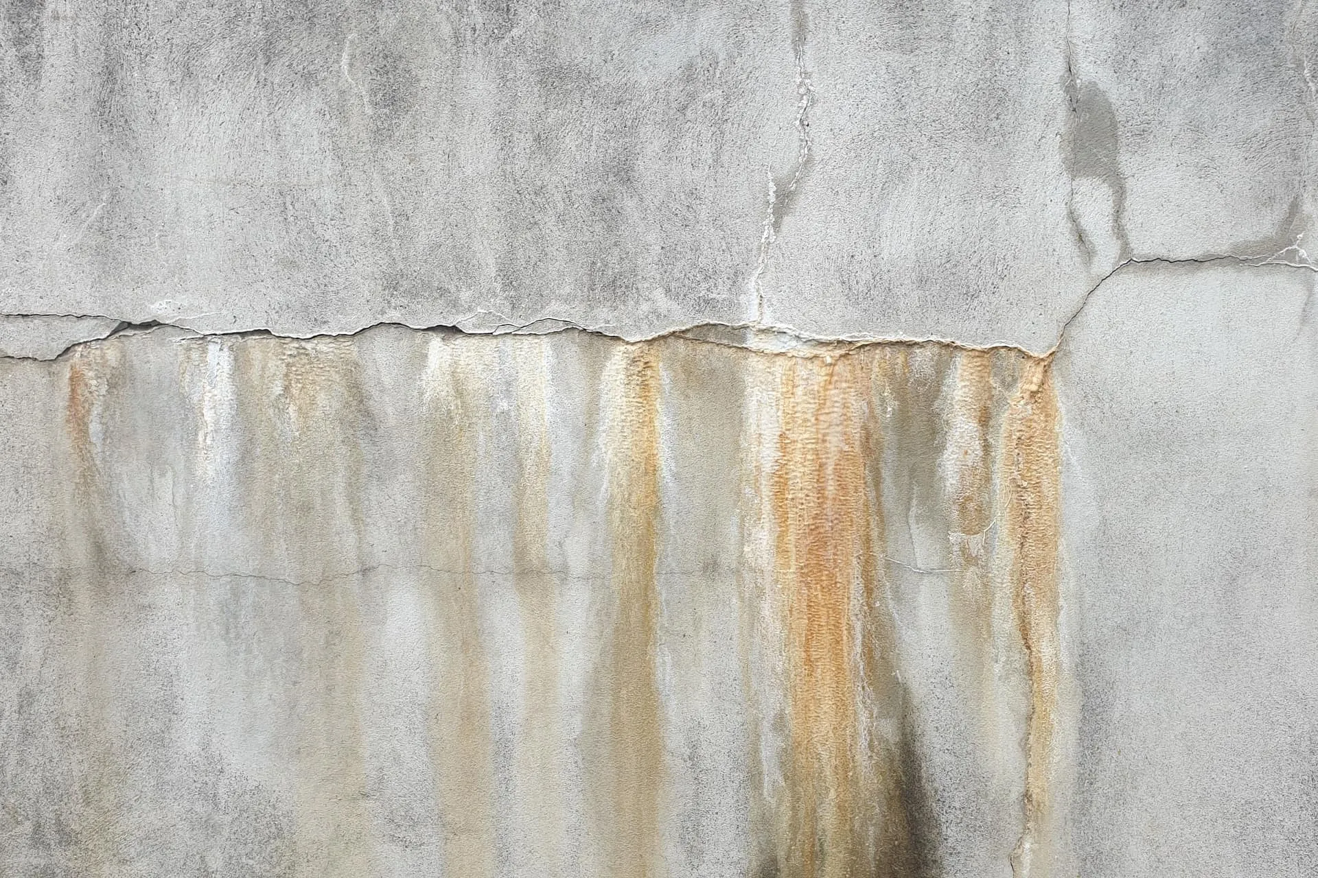 Water stains and streaks below a crack in a wall, a sign needing water leak detection