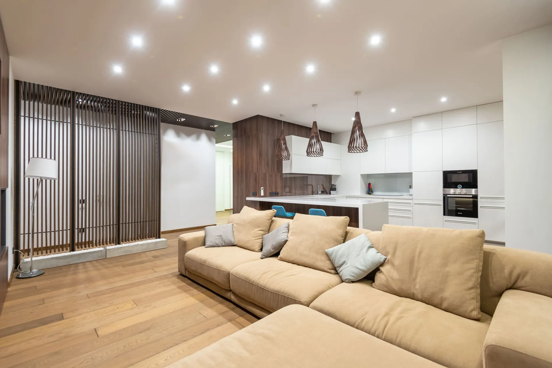Open-plan living room and kitchen lit by a grid of LED downlights after downlight installation