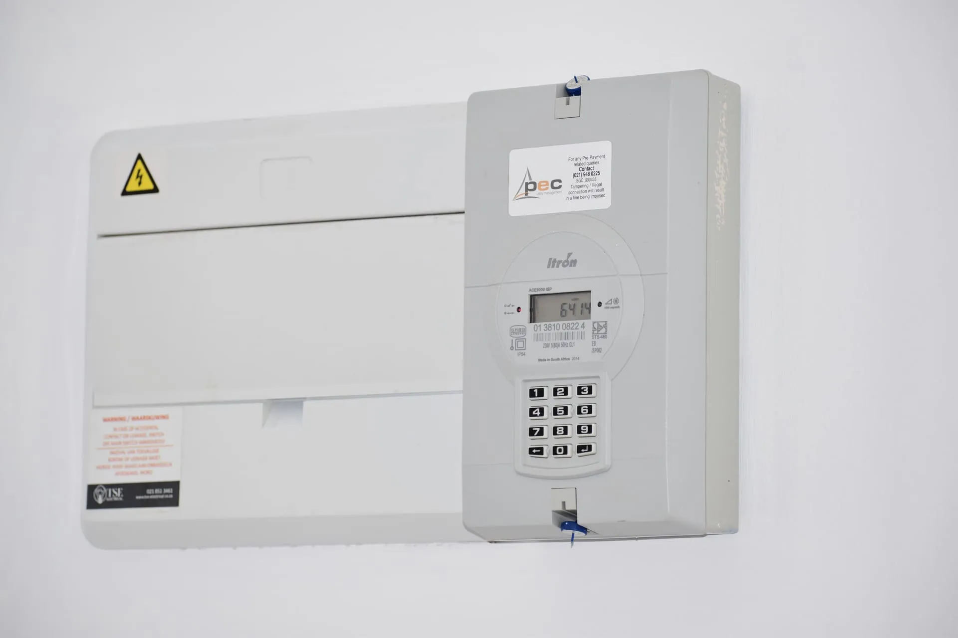 Wall-mounted electricity meter and fuse box, central to single phase vs three phase power