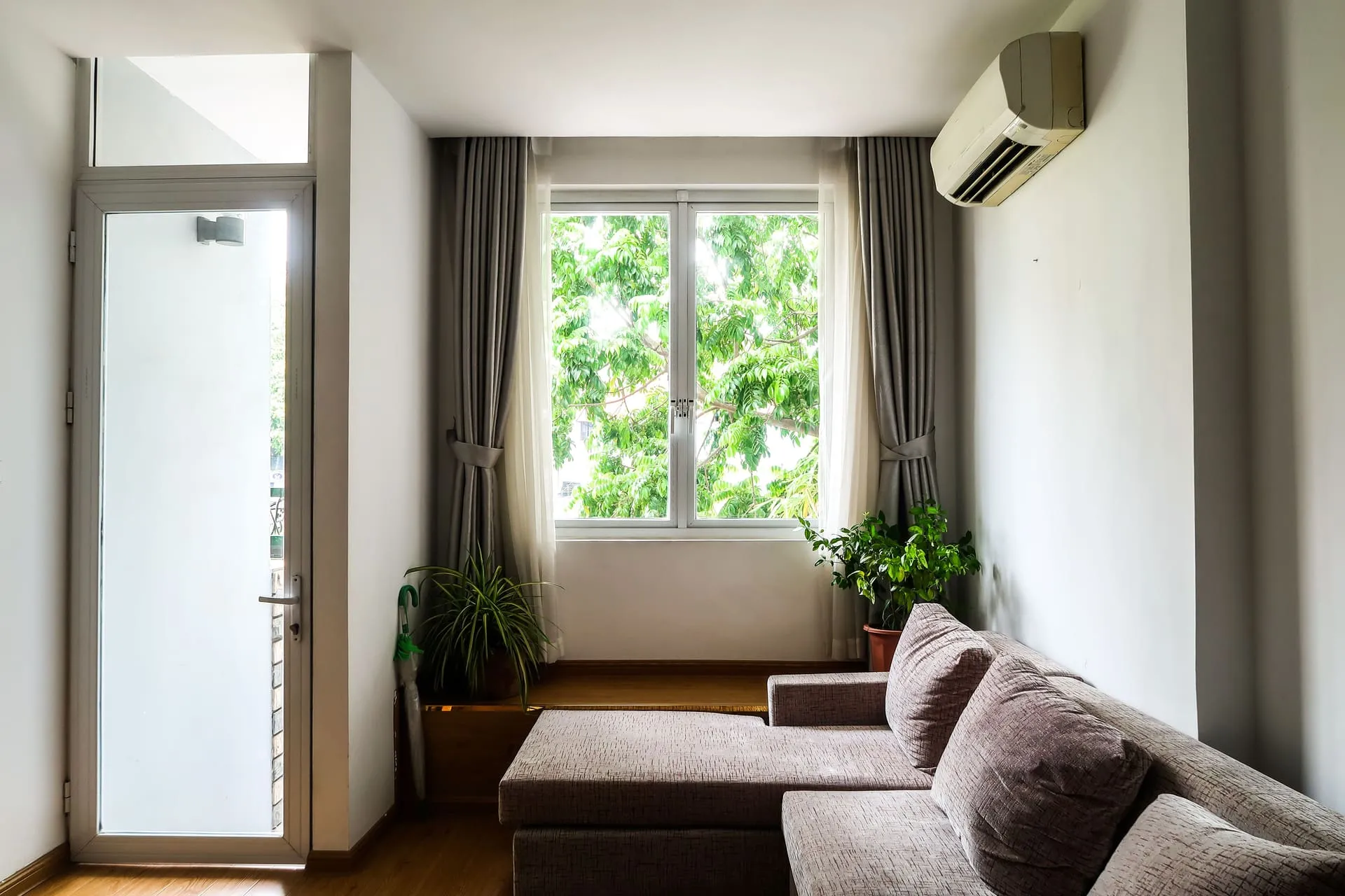 Split system air conditioner mounted high on a living room wall above a sofa